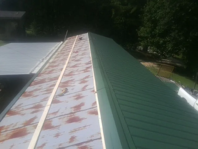 Old rusted panels beside newly installed green metal roofing — Wind Damage Roof Repair by Roofing Brothers in West Salem
