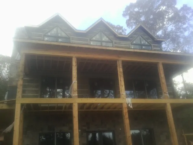 Dormers and porch framing on a large log home under construction — Roof Coating work by our crew in West Salem