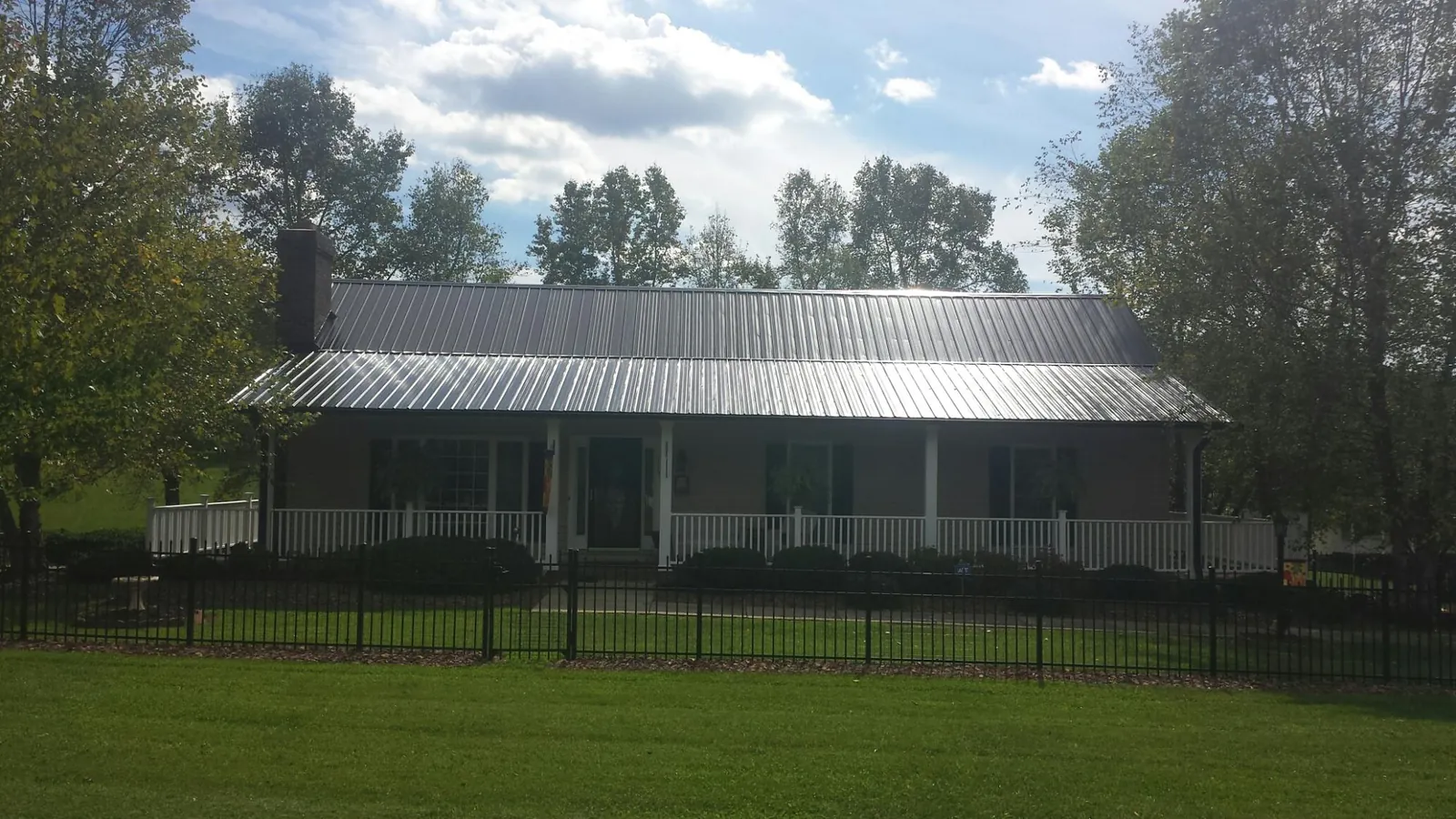 Gray metal roof on a brick ranch with a full width front porch — Gutter Guard Installation work by our crew in West Salem