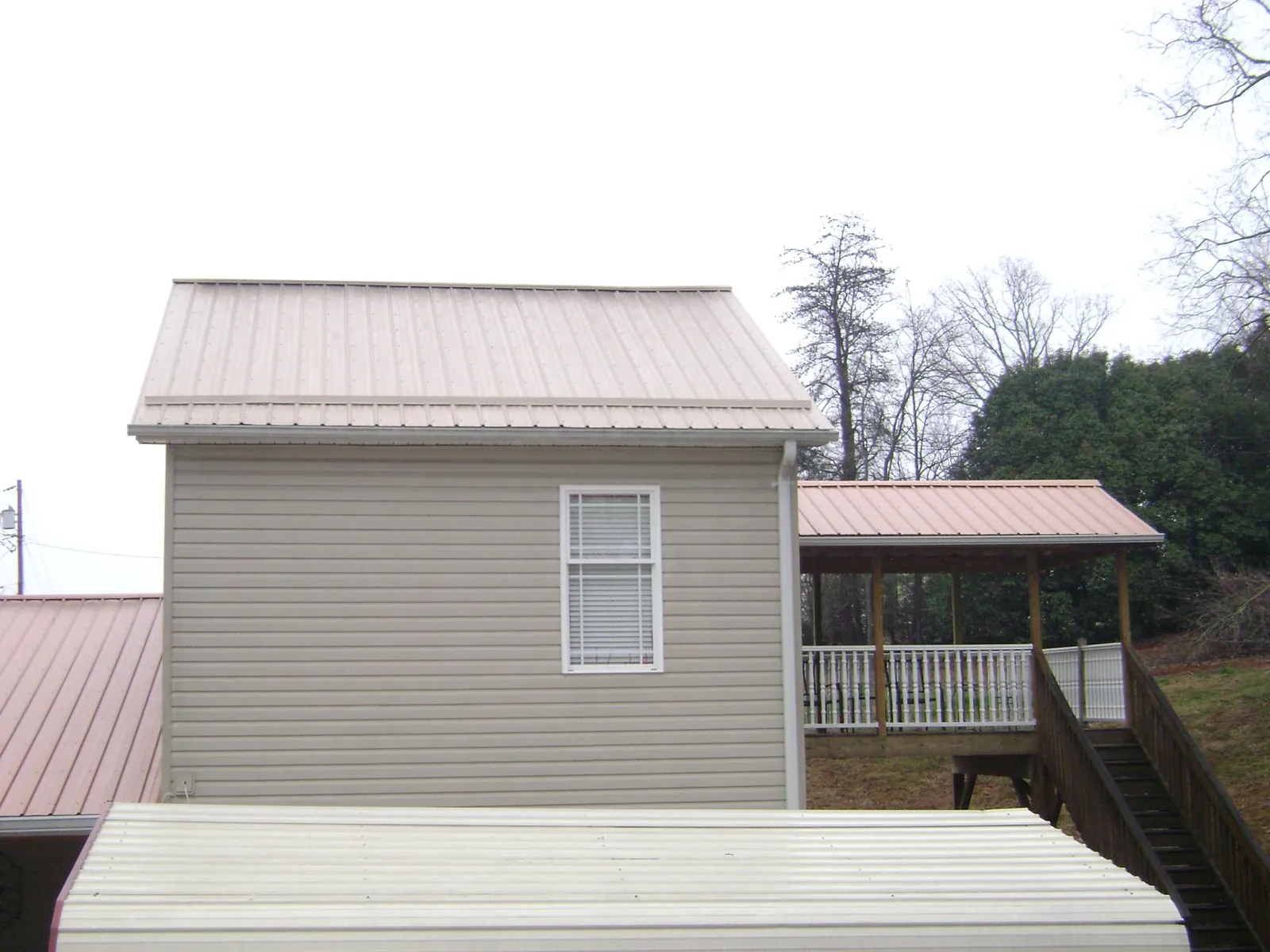 Tan metal roofs on a two story addition and attached porch, from a Roof Replacement job in West Salem